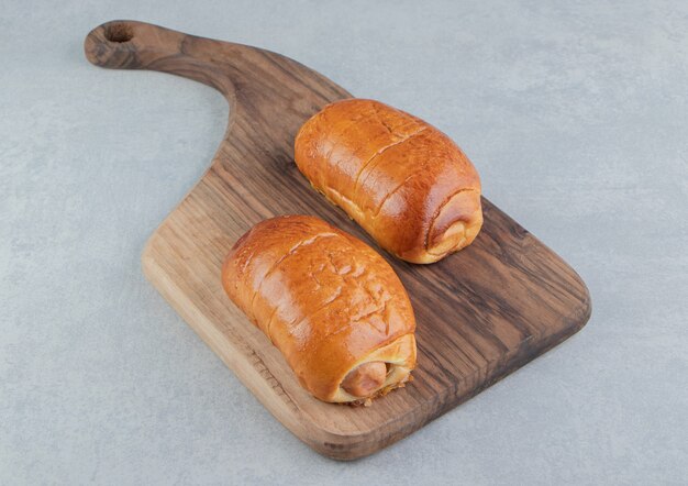 De délicieuses pâtisseries avec des saucisses sur planche de bois.