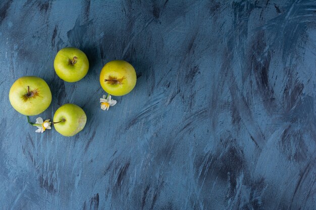 De délicieuses pommes fraîches vertes placées sur une table bleue.