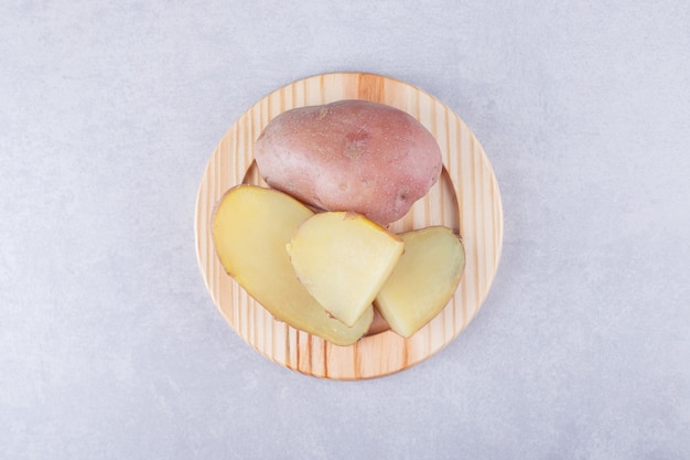 De délicieuses pommes de terre bouillies sur une assiette en bois.