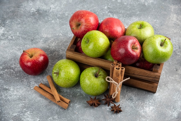 De délicieuses pommes vertes et rouges entières dans une boîte en bois.