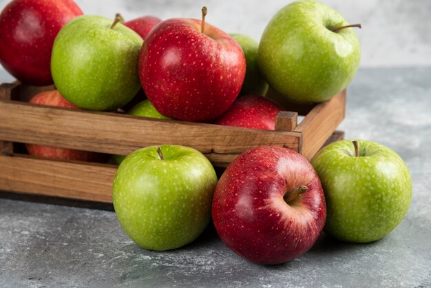 De délicieuses pommes vertes et rouges fraîches dans une boîte en bois.