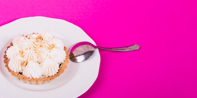 Délicieuses tartes à la meringue sur une plaque blanche sur fond rose