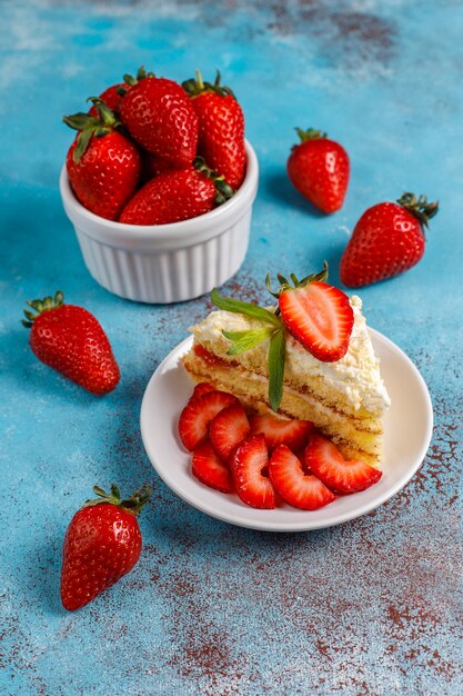 Délicieuses tranches de gâteau aux fraises maison avec de la crème et des fraises fraîches