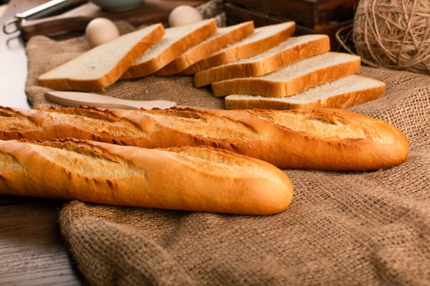 Délicieuses tranches de pain avec baguette sur nappe