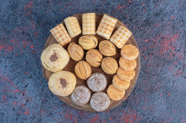 Un délicieux assortiment de pâtisseries sur une planche de bois sur un tableau abstrait.