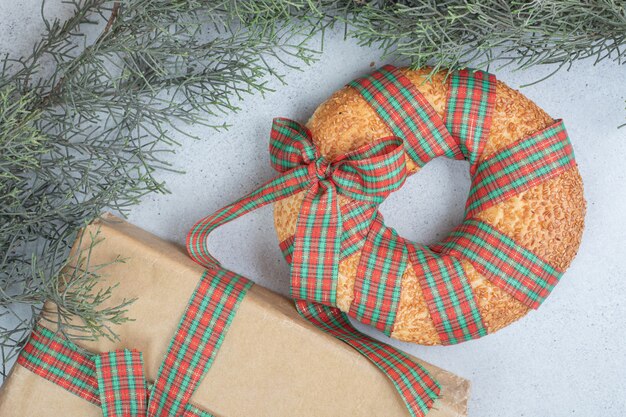 Délicieux bagel sucré noué dans un arc festif avec un cadeau de Noël