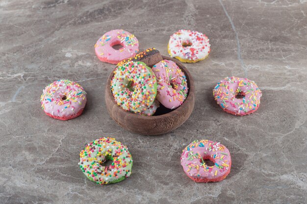 De délicieux beignets dans et autour d'un petit bol sur une surface en marbre