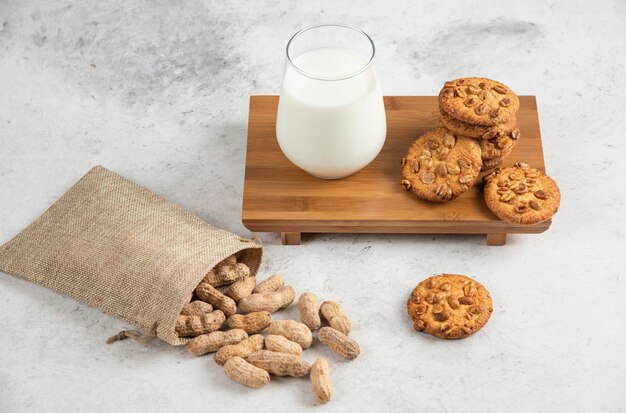 Délicieux biscuits au miel et aux arachides et verre de lait sur planche de bois.