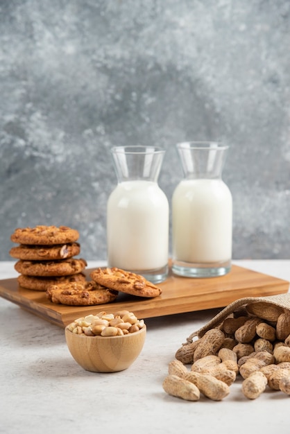 Délicieux biscuits aux cacahuètes biologiques et verre de lait sur planche de bois.