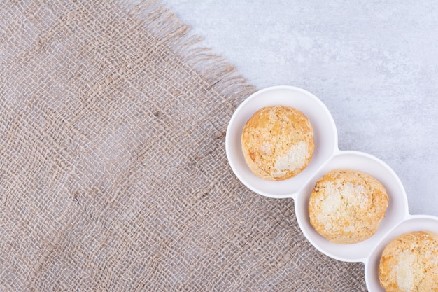 Délicieux biscuits dans des bols blancs avec de la toile de jute