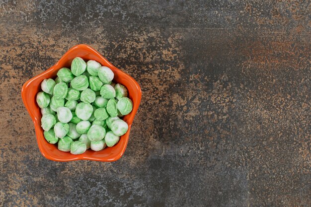 Délicieux bonbons au menthol vert dans un bol orange.