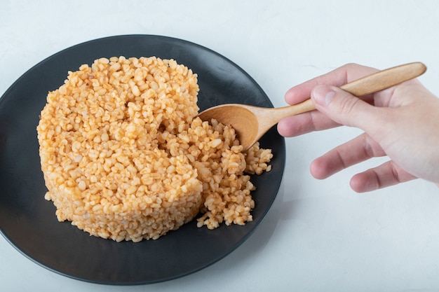 Délicieux boulgour pilaf sur assiette sombre.