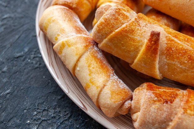 Délicieux bracelets sucrés avec garniture à l'intérieur de la plaque sur une pâte à gâteau biscuit sucré foncé