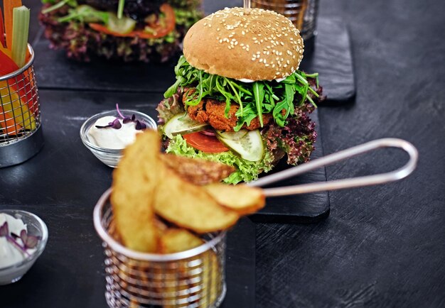 Délicieux burger, frites avec salade sur une table.