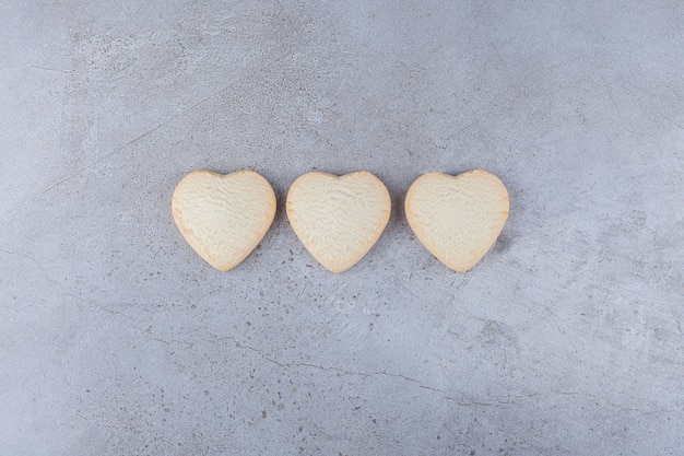 Photo gratuite délicieux cookies en forme de coeur placés sur une table en pierre.