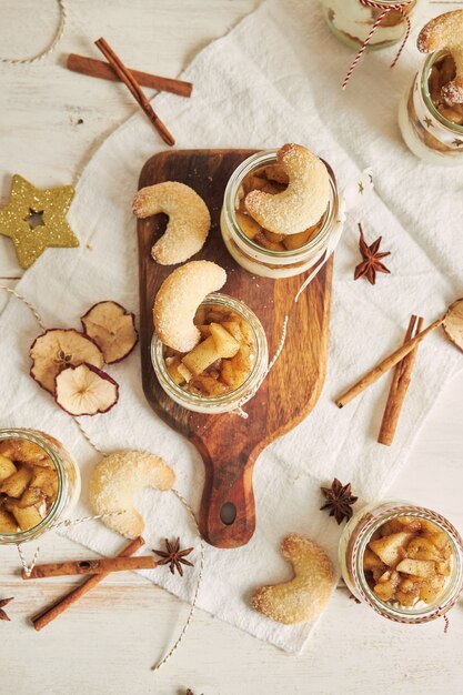 Délicieux dessert de biscuits de Noël avec pomme au four et crème sur une assiette en bois sur une table blanche