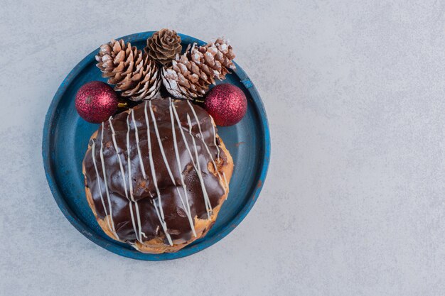 Délicieux éclair et boules de Noël sur plaque bleue.