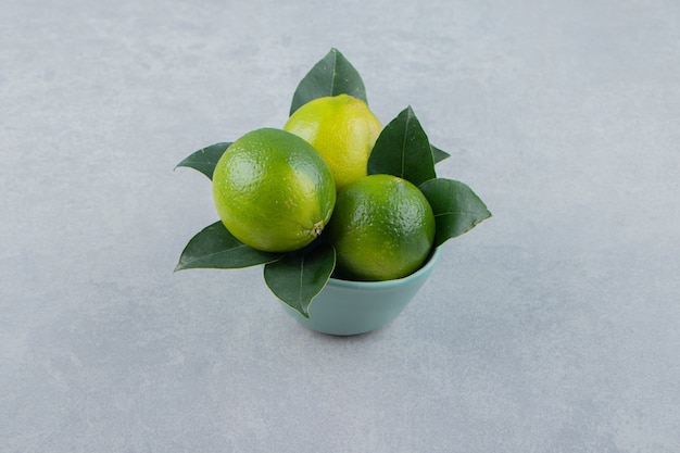 De délicieux fruits de citron vert dans un bol bleu