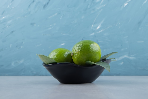 De délicieux fruits de citron vert dans un bol noir