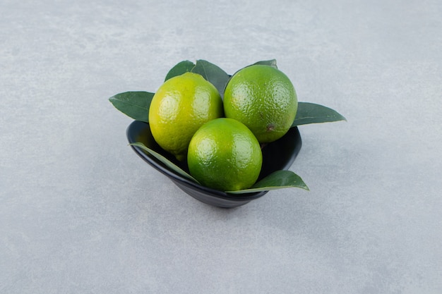 De délicieux fruits de citron vert dans un bol noir