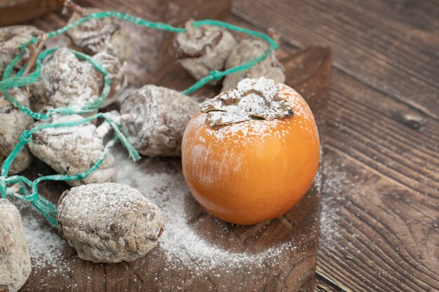 Délicieux fruits de kaki frais et séchés sur planche de bois