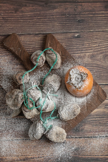 Délicieux fruits de kaki frais et séchés sur planche de bois