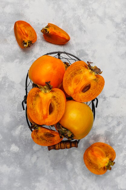 Délicieux fruits mûrs de kaki sur béton