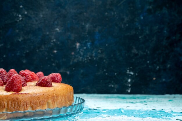 Délicieux gâteau aux fraises en forme ronde avec des fruits sur le dessus sur un bureau bleu vif, pâte à gâteau biscuit sucré sucre fruit berry