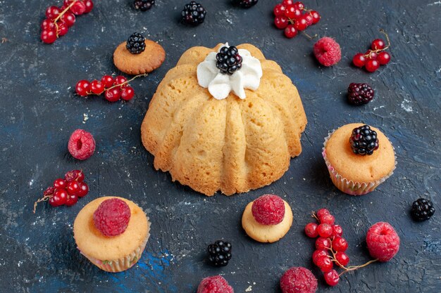 Délicieux gâteau sucré avec des baies et de la crème délicieuse avec des canneberges réparties sur un bureau sombre, biscuit gâteau aux baies