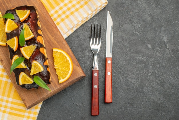 Photo gratuite délicieux gâteaux moelleux sur planche de bois et citrons coupés avec des feuilles sur une serviette à rayures vertes