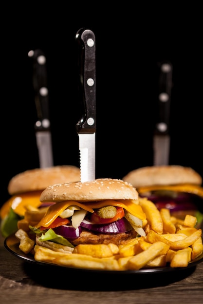 De délicieux hamburgers gastronomiques sur plaque noire à côté de frites. Fast food. Collation malsaine