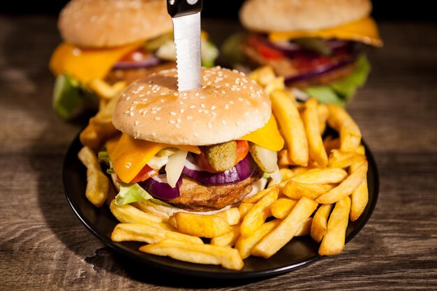 De délicieux hamburgers gastronomiques sur plaque noire à côté de frites. Fast food. Collation malsaine
