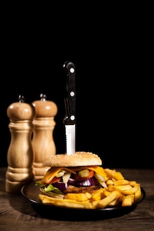 De délicieux hamburgers savoureux faits maison sur fond noir et bois. nourriture rapide et savoureuse