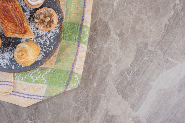 Délicieux kyata entouré de biscuits surmontés de lokums et de pommes de pin sur une planche en marbre.