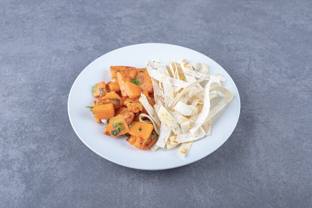 Délicieux lavash en tranches et carottes cuites au four dans une assiette, sur la surface en marbre.