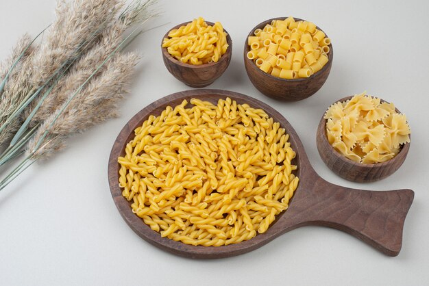 Délicieux macaronis crus sur plaque en bois