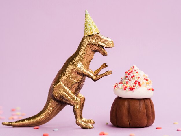 Délicieux muffin et dinosaure avec chapeau de fête