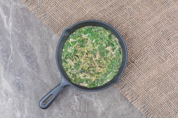 De délicieux œufs au plat avec des légumes verts sur une poêle sombre sur un sac. photo de haute qualité