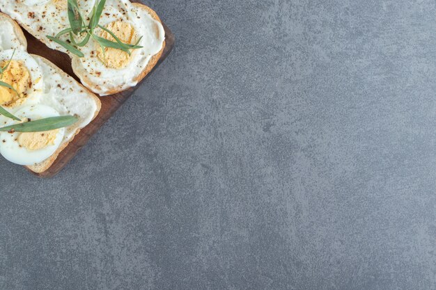 Délicieux œufs durs avec du pain grillé sur planche de bois.