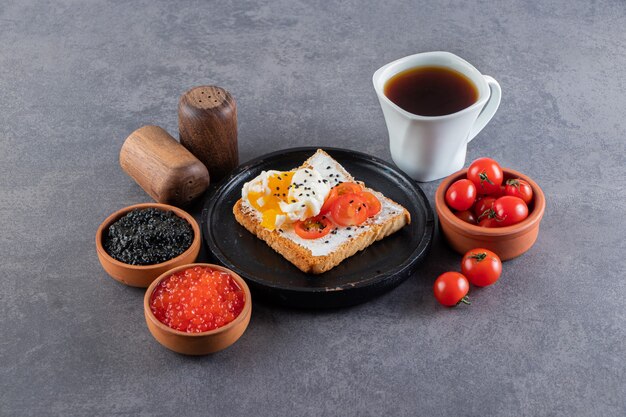 Délicieux pain grillé avec des tomates cerises rouges fraîches et une tasse de thé.