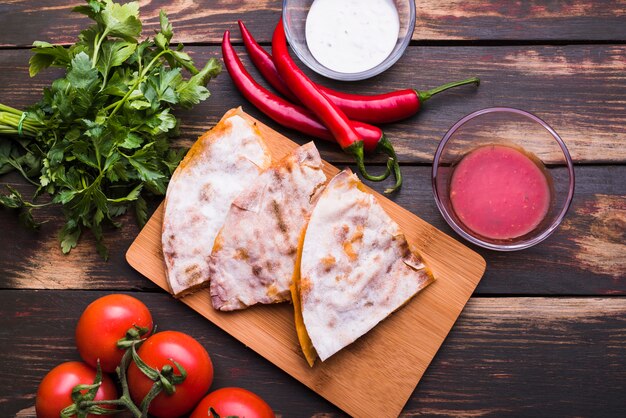 Délicieux pita sur une planche à découper près de sauces parmi des légumes et des herbes