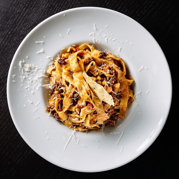 Délicieux plat de pâtes fettuccine garni de fromage râpé sur une assiette blanche