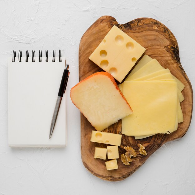 Délicieux plateau de fromages et laiterie vierge en spirale avec un stylo sur fond Uni