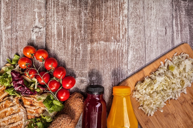 Photo gratuite délicieux poulet grillé sain sur planche de bois à côté de pain sain, de tomates et de salade. mode de vie sain et alimentation