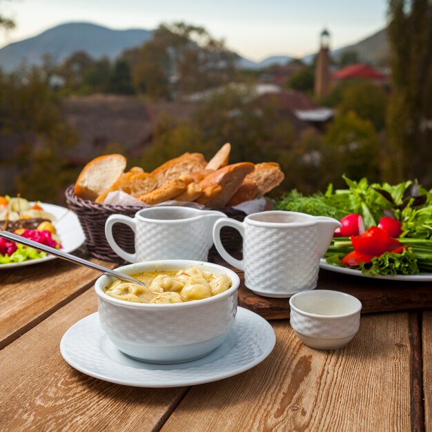 Délicieux repas de soupe avec pain, légumes verts, salade dans un bol avec village en arrière-plan, high angle view.