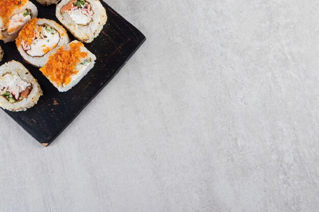 De délicieux rouleaux de sushi frais placés sur une planche de bois sombre.