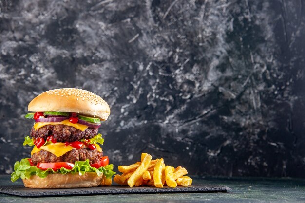 Délicieux sandwich et frites sur un plateau de couleur sombre sur le côté droit sur une surface noire