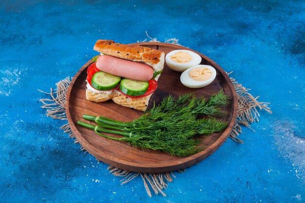 Délicieux sandwich avec des saucisses et de l'aneth sur une plaque en bois.