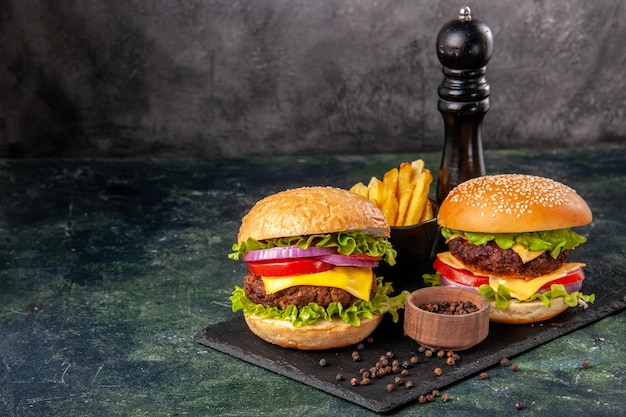 De délicieux sandwichs faits maison sur une planche à découper noire frites du poivre sur une surface floue gris foncé