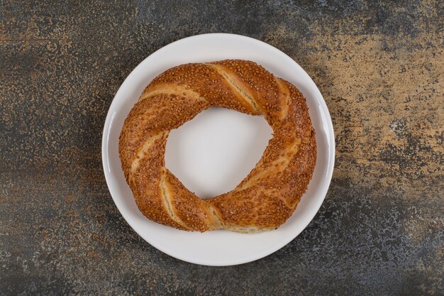 Délicieux simit aux graines de sésame sur plaque blanche.